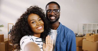 Afrikalı Amerikalı mutlu çiftin video kaset çekerken, konuşurken ve yeni bir daireden anahtarlarıyla hava atarken. Taşınırken oda. Bakış açısı. Portre fotoğrafı. Kapalı