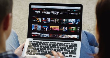 New York - 01 Aralık 2017: Kafkas erkek ve kadın Netflix web sitesinde kayan üst omuz görünümünü kapatın ve dizüstü bilgisayardan bir dizi izlemeye başlayın. Üst görünüm