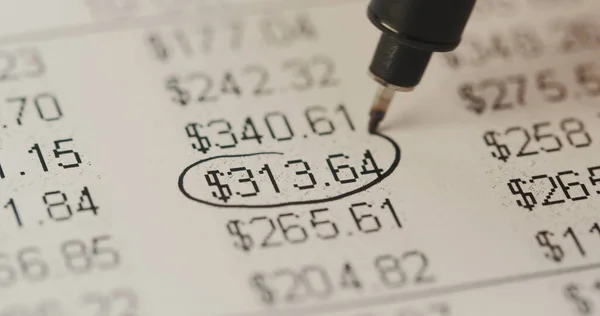 Close up of the table with numbers, currencies and per cents lying on the table and hand encircling them with black colour. Macro shooting Stock Picture