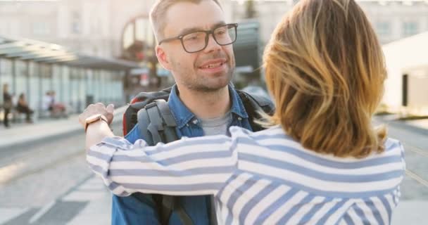 Kavkazský muž turista s batohem setkání krásné šťastné manželky po dlouhé odloučení. Zadní část krásné usměvavé ženy přijíždí přivítat svého manžela z výletu, objímat a objímat. — Stock video