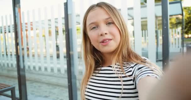 POV de Caucásico hermosa niña adolescente de pie en la parada de autobús y hablando a través de la webcam. Bastante alegre shoolgirl tener videochat en gadget de teléfono celular en la estación de tren. Videograbando. De cerca.. — Vídeo de stock