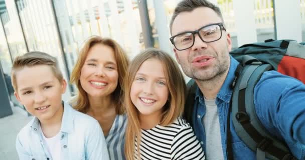 Punto di vista della giovane famiglia felice caucasica con piccoli ragazzi che fanno videochat, sorridono e salutano con le mani all'aperto. Madre, padre e bambina e ragazzo parlando con la fotocamera come videochat. — Video Stock