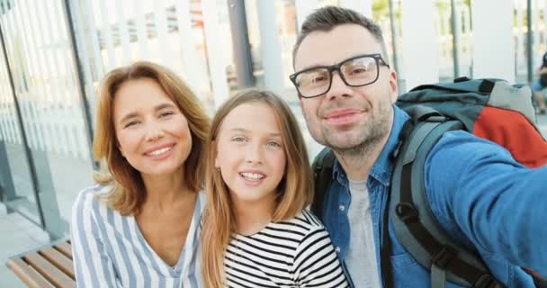 Punto di vista della giovane famiglia felice caucasica con una piccola figlia adolescente che fa videochat, sorride e saluta con le mani all'aperto. Madre, padre e bambina che parlano con la telecamera come videochat. — Video Stock