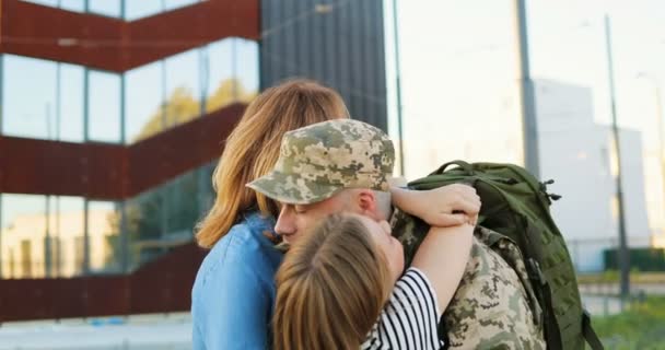 Happy young Caucasian father officer meeting and hugging cute small kid and wife at street. Handsome male soldier in uniform coming back from army and meeting woman with daughter War service returning — Stock Video