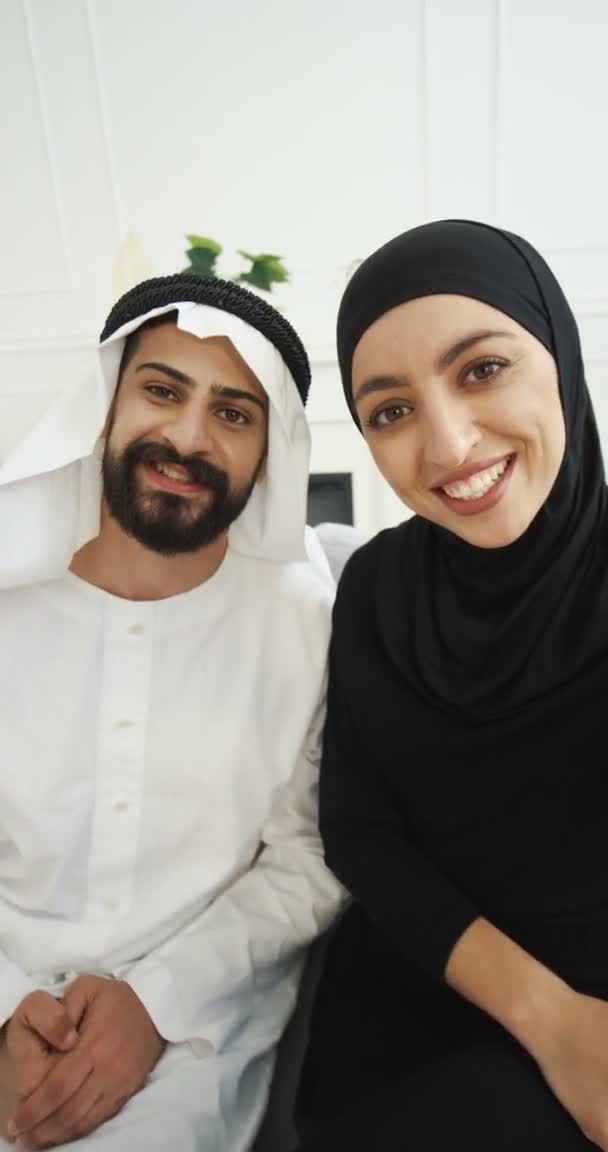 Árabes musulmanes casados pareja hablando con la cámara cuando se tiene videochat. Hombre y mujer árabes videochat y sonriendo en la webcam. Medio Oriente. Disparo de orientación vertical. material de archivo para historias. — Vídeos de Stock