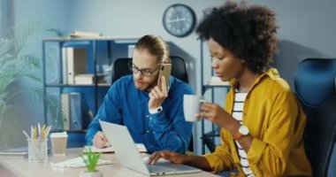 Çok ırklı işçiler. Güzel Afro-Amerikan iş kadını kahve içiyor ve ofisteki dizüstü bilgisayarında yazıyor. Kafkasyalı yakışıklı adam akıllı telefonla konuşuyor ve planlamacıyla yazıyor..