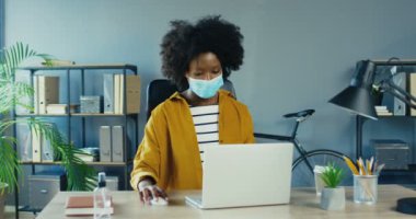 Güzel bir Afro-Amerikalı iş kadını, iş yerinde otururken dizüstü bilgisayarında daktilo kullanıyor. Güzel kıvırcık kız internette interneti arıyor ve kabine odasına bakıyor. Görev konsepti