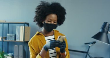 İş yerinde akıllı telefondan koruyucu yüz maskesi takan Afro-Amerikan güzel bir kızın portresini yakından çek. Dolapta cep telefonuyla mesaj atan güzel bir bayan ofis çalışanı. Çalışma konsepti