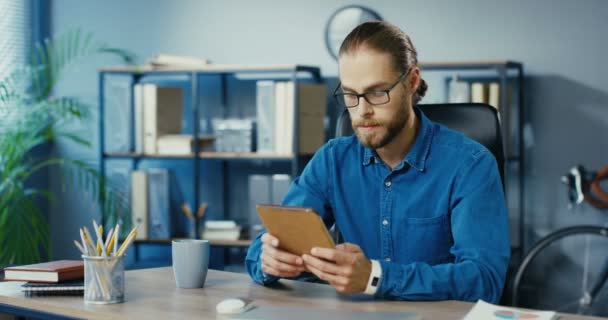 Bon homme d'affaires occupé à la recherche de lunettes Internet sur l'appareil tout en étant assis sur le lieu de travail. Beau professionnel masculin caucasien au travail tapant et faisant défiler sur la tablette dans l'armoire Concept de bureau — Video