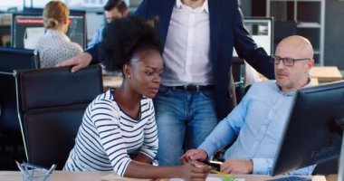 İki ofis çalışanı: Afro-Amerikalı kadın ve yetişkin Avrupalı erkek ortak bir görev için grup halinde çalışıyorlar. Koordinatör öğrencilere yaklaşıyor ve tavsiyelerde bulunuyor..