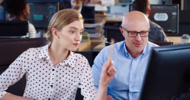 Genç ve güzel kadın ekonomist ofiste otururken kıdemli uzman ile birlikte çalışıyor..