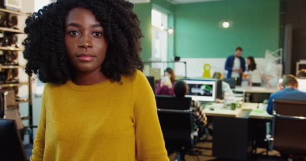 Ritratto ravvicinato di giovane bella donna afroamericana in maglione giallo. Lavoratrice con i capelli ricci sorride con le braccia incrociate. — Video Stock