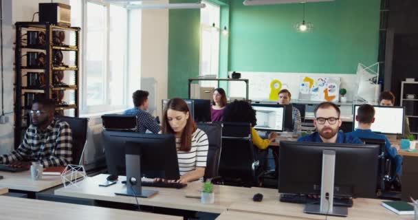 オフィスに座ってコンピュータで働く男女の一般的な計画。チームは同僚で働いている。近代事務所. — ストック動画