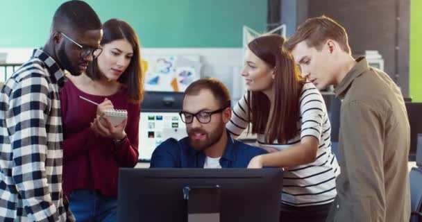 Equipo joven de profesionales haciendo una lluvia de ideas cerca de la computadora en la oficina. Dos mujeres y tres hombres están trabajando juntos en el proyecto. — Vídeos de Stock