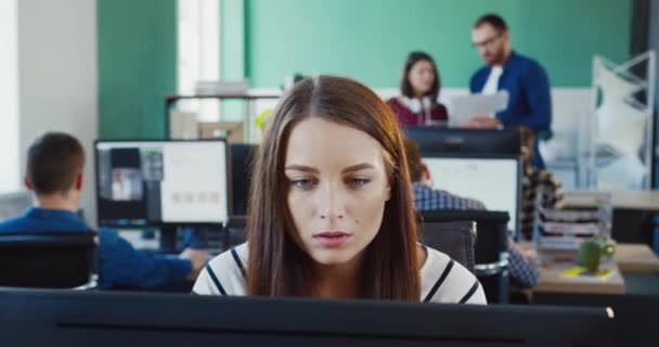 Ofiste bilgisayarla yazı yazan genç ve güzel bir kadının portresini yakından çek. Kadın çevrimiçi danışman, yönetici veya programcının işi. — Stok video