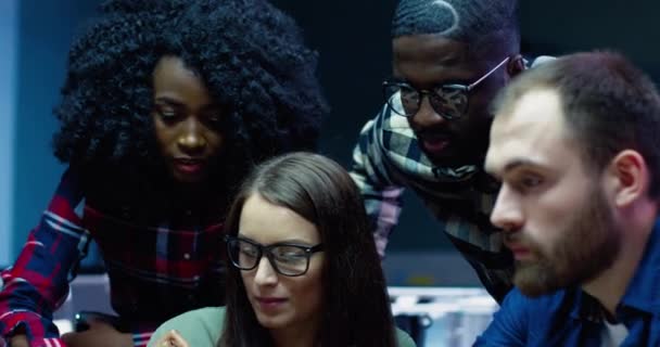 Grupa pracowników biurowych zebrała się w pobliżu miejsca pracy i przeprowadziła burzę mózgów projektu. Piękna Afroamerykanka z kręconymi włosami bierze ołówek i dostosowuje wpisy na papierze. — Wideo stockowe