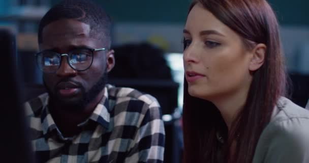 Close up of african american man and pretty girl looking at monitor screen sitting in office and discussing project work. — Stock Video