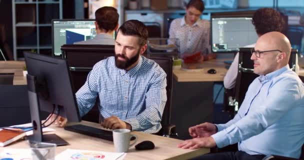 2人の大人の男性が事務所に座って仕事に取り組んでいます。同僚は成功した結果に満足しています. — ストック動画