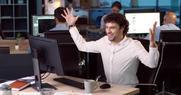 Az irodai dolgozó fehér ingben nézi a képernyőt és jó híreket kap. Az ember érzelmileg boldog a sikertől. A csapat elégedett a győzelemmel.. — Stock videók