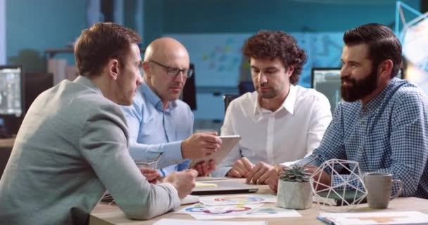 Grupp affärs analytiker sitter vid bordet med dokument. Två vuxna män undertecknar avtal genom att skaka hand. — Stockvideo