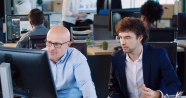 Ofiste otururken proje üzerinde çalışan iki beyaz adam. Genç çalışanlar hatalara dikkat çekiyor. Takım çalışması beyin fırtınası.