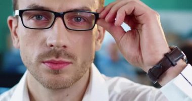 Beyaz gömlekli, gözlüklü, kar beyazı gülüşlü ve kameraya bakan yakışıklı genç bir uzmanın portresi..