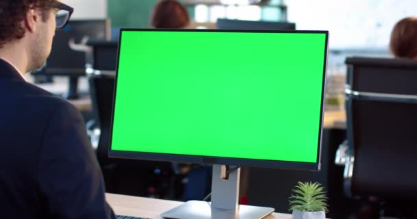 Zamknij monitor w biurze. Zielony ekran. Pracownik pracujący przy komputerze, siedzący przy biurku. Widok z tyłu. — Wideo stockowe
