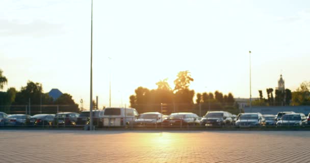 Caucasiano ciclista masculino no pôr-do-sol ao ar livre. Elegante homem bonito andando de bicicleta e cruzando estacionamento. Carros no fundo. Cara tendo passeio na noite de verão agradável na cidade. — Vídeo de Stock
