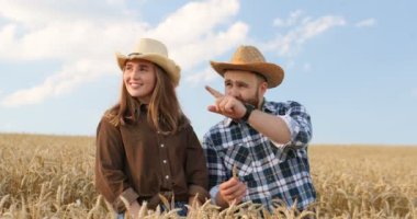 Beyaz tenli yakışıklı erkek çiftçinin portresi ve buğday tarlasında yürüyen güzel neşeli genç kız. Sakallı vatandaş dışarıda kadınlara bir şey gösteriyor ve açıklıyor. Konuşma konsepti
