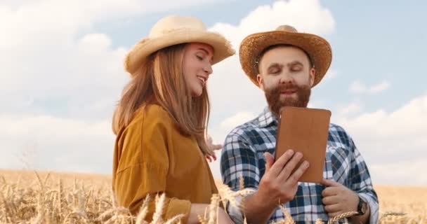 描述快乐的白人英俊男人和美丽女人站在农场外面 在电视上聊天的景象 戴着帽子的男男女女在战场上的平板电脑上通过视频通话 谈话概念 — 图库视频影像