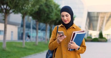 Genç Arap tesettürlü güzel bir kız ders kitaplarıyla sokakta yürüyor, cep telefonundan mesaj yolluyor. Başörtüsü takmış güzel müslüman bir kız öğrenci şehirde geziniyor, kitap tutuyor, telefonla dinliyor..
