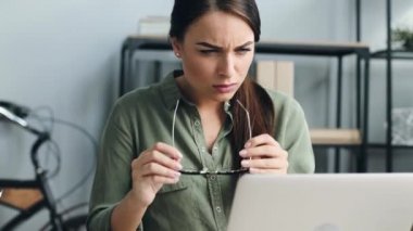 Genç ve güzel bir kıza yaklaş gözlük tak ve dizüstü bilgisayar ekranına yakından bak. Odaklanmış kadın çalışma belgesinde hata buldu.