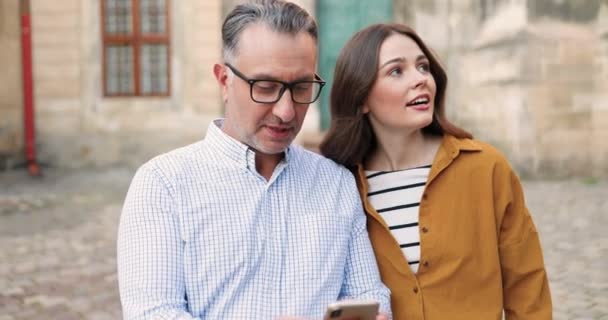 Kaukázusi Apa Szemüvegben Sétál Utcán Felnőtt Gyönyörű Lányával Okostelefon Térképet — Stock videók