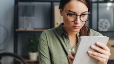 Tabletten hoşlanan genç bir kadının portresi. Öğle arasında elektronik cihazda gözlüklü kadın oyuncu oyunu.