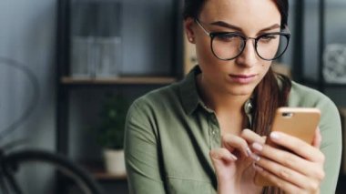 İş yerinde akıllı telefon kullanan genç bir kadının portresini kapat. Çekici kız telefonda mesaj yazıp, kaydırıyor..