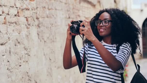 近景肖像年轻的非洲裔美国女游客卷发。美丽的女孩走过新城，用相机拍照. — 图库视频影像