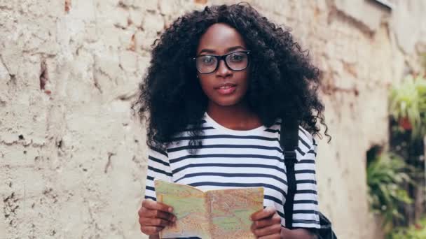 Close up retrato de jovem bela menina turista afro-americana olhando para o mapa de pé na rua. Mulher feliz posando para câmera e sorrindo. — Vídeo de Stock