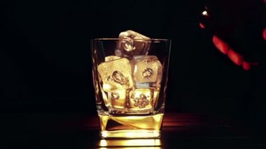 barmen ahşap masa ve siyah koyu arka plan üzerinde buz küpleri ile cam içine dökme viski, buz küpleri, viski odak dinlenmek zaman sıcak bir atmosfer