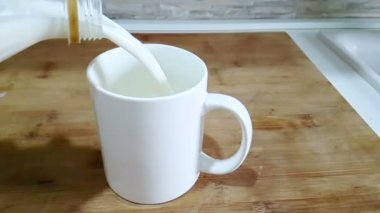 mutfak arka planda, ağır çekim, diyet ve sağlıklı beslenme kahvaltı konsepti ile çekim cam içme içine dökme taze beyaz süt