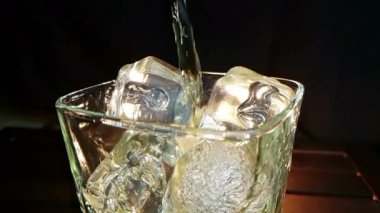 barmen ahşap masa ve siyah koyu arka plan üzerinde buz küpleri ile cam içine dökme viski, buz küpleri, viski odak dinlenmek zaman sıcak bir atmosfer