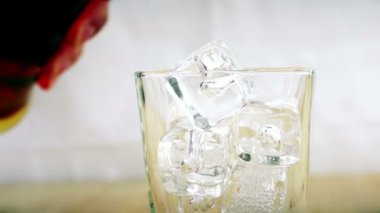 ahşap masa arka plan, odak üstünde buz, buz küpleri ile cam içine dökme viski barmen viski dinlenmek zaman, altın sıcak ortam