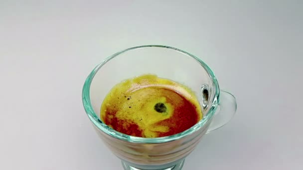 コーヒー白い光の背景 食品の泡とエスプレッソ コーヒーのカップをあふれる中スローモーションで落ちるドロップを飲むし リラックスのコンセプト — ストック動画