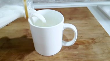 mutfak arka planda, ağır çekim, diyet ve sağlıklı beslenme kahvaltı ile çekim cam içme içine dökme taze beyaz süt