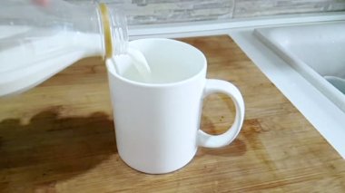 mutfak arka planda, ağır çekim, diyet ve sağlıklı beslenme kahvaltı ile çekim cam içme içine dökme taze beyaz süt
