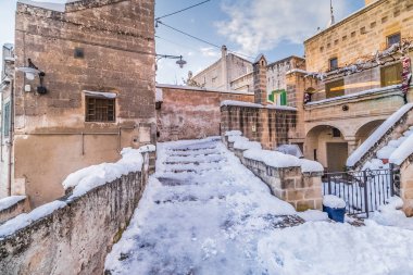 panoramik manzaralı tipik Sassi di Matera ve kilise Matera 2019 bulutlar ve kar ile mavi gökyüzü altında eve, seyahat ve Noel tatil kavramı üzerinde kar taneleri, Avrupa Kültür 201 başkenti taşlar