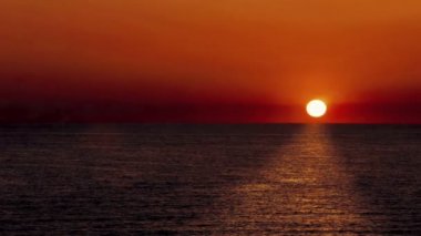 Deniz sakin ve güneş ile günbatımı manzara geride