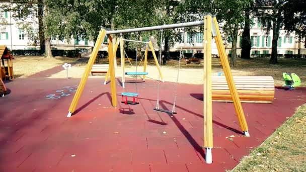 Columpios vacíos con cadenas balanceándose en el patio de recreo para el niño, movido del viento, lento — Vídeo de stock