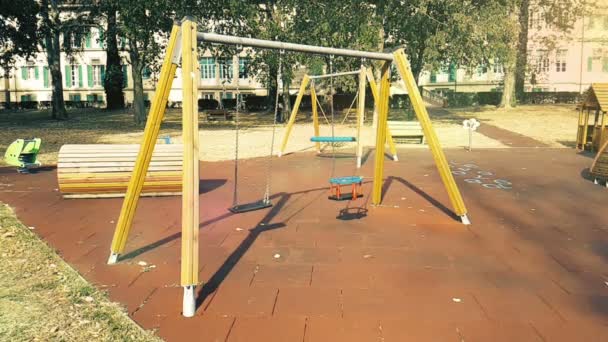 Leere Schaukeln mit schwankenden Ketten auf Kinderspielplatz, vom Wind bewegt, langsam — Stockvideo