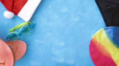 Havuz veya fitness kulübü için Noel arka plan. Yüzme gözlükleri, yüzme şortları ve parmak arası terliklerin yanı sıra yüzme şapkalı Noel Baba şapkası. Yeni Yılınız Kutlu Olsun