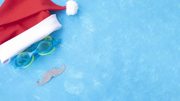 Afiş. Yüzme ve kırmızı dudaklar için gözlük ile Noel Baba şapka. Yüzme Havuzu yakınındaki su, terlik ve havuz gözlükleri ile yılbaşı tatili, sandalet ve yüzme gözlükleri